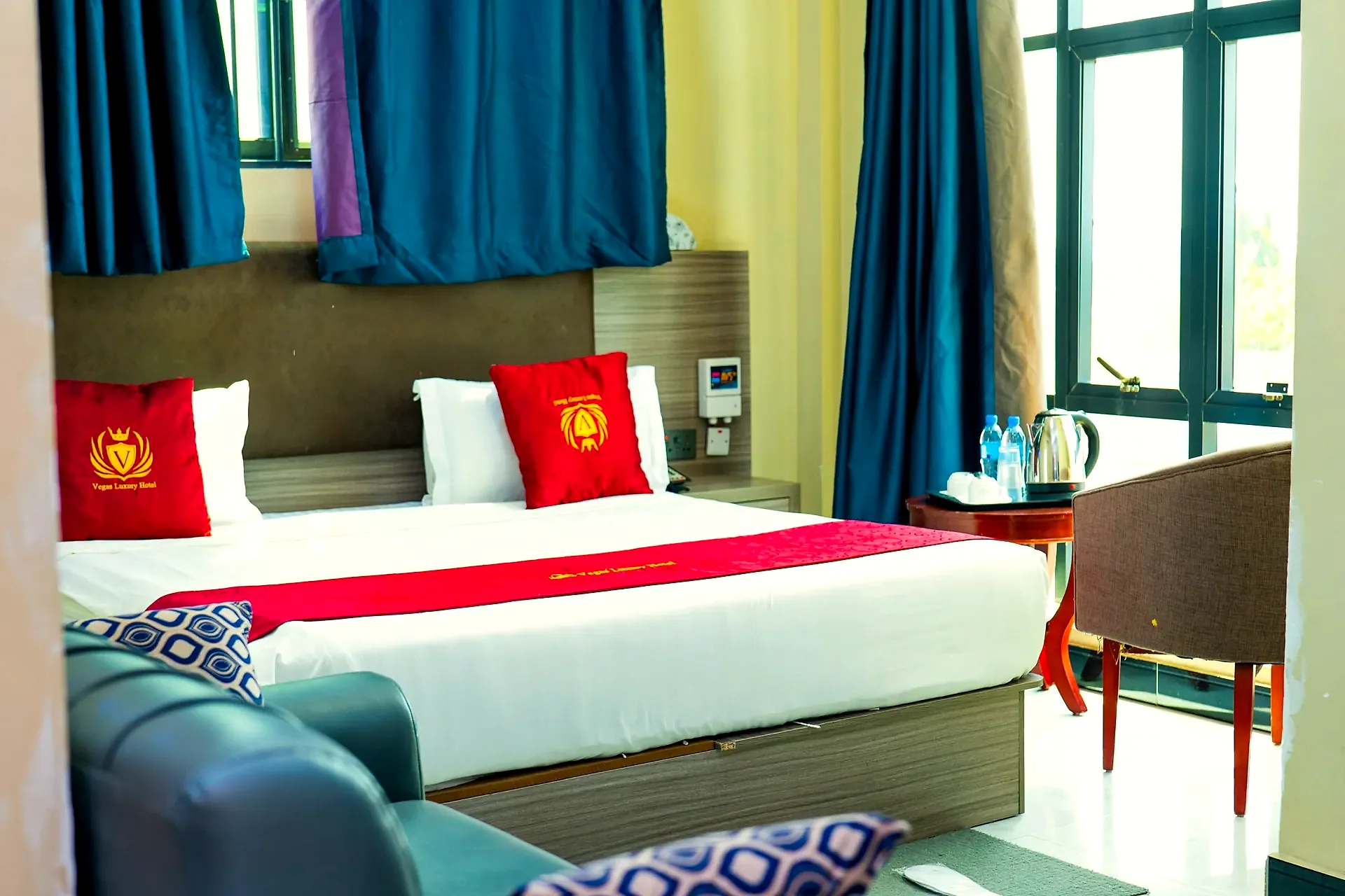Guest room with red and gold Vegas Luxury Hotel linens and tall windows